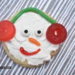 Top view of a sugar cookie decorated as a snowman's face with candy earmuffs