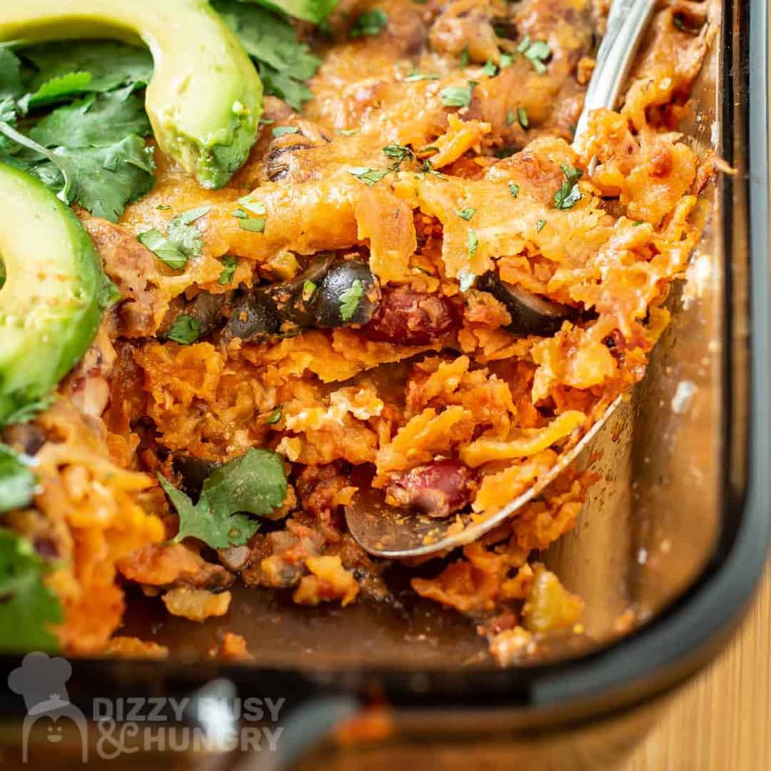 Close up shot of layers in dorito casserole being held by a spoon in the pan.