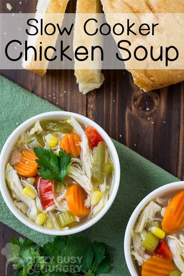 Overhead shot of chicken soup in a green bowl on a green napkin with sliced bread in the background.