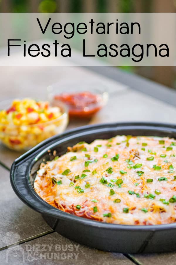 Side view of fiesta lasagna garnished with green onions in a black pan.