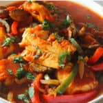 Closeup view of cod fish cooked in a tomato and onion sauce