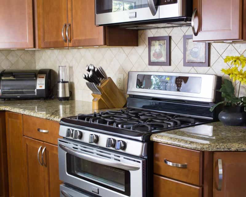 photo of a kitchen stove and granite countertops, with blender, toaster oven, and knife set.