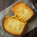 Overhead view of an oven-grilled cheese sandwich showing a gooey, stretchy cheese pull.