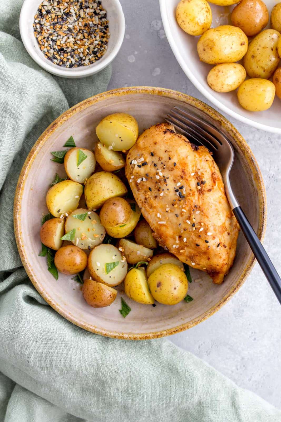 bowl of instant pot chicken breasts with a side of potatoes.
