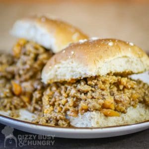 Side view of two sloppy joe sliders on a white plate.