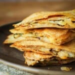 Close up shot of vegetarian quesadillas stacked on a brown plate.