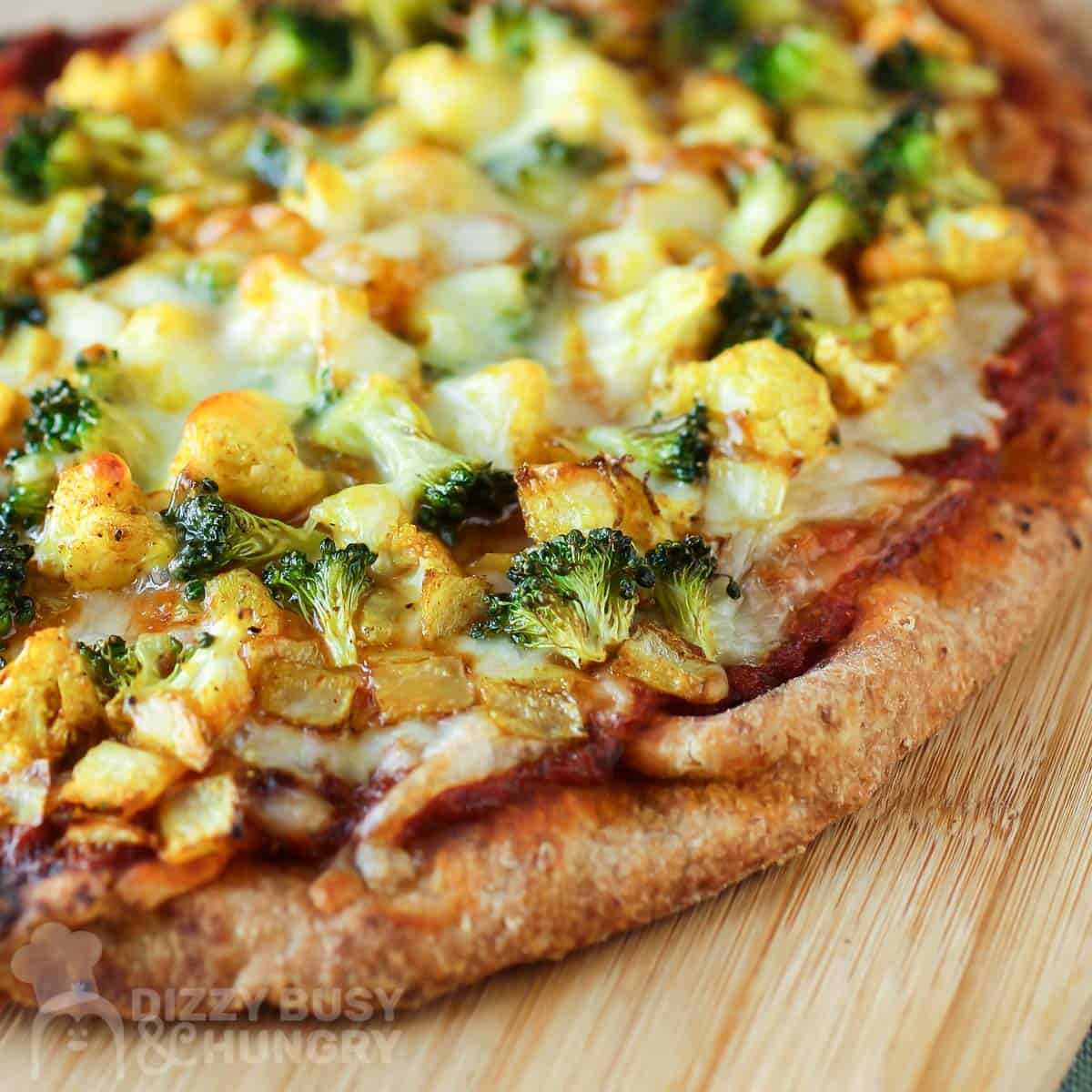 Close up shot of uncut pizza on a wooden cutting board.