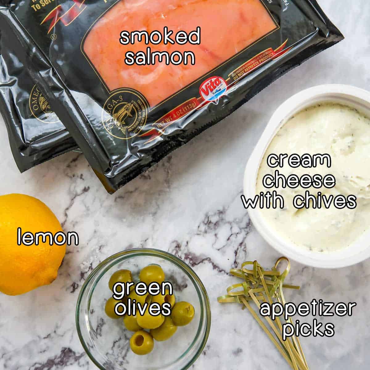 Overhead shot of ingredients- smoked salmon, cream cheese with chives, lemon, green olives, and appetizer picks.