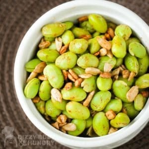 Close up overhead shot of chipotle edamame in a white bowl on a brown surface.