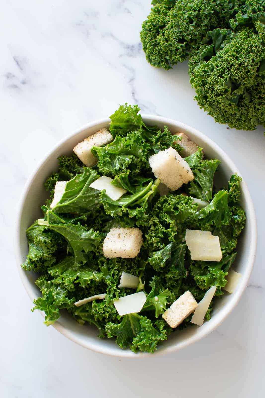 A bowl of kale salad with lemon dressing, croutons and Parmesan.