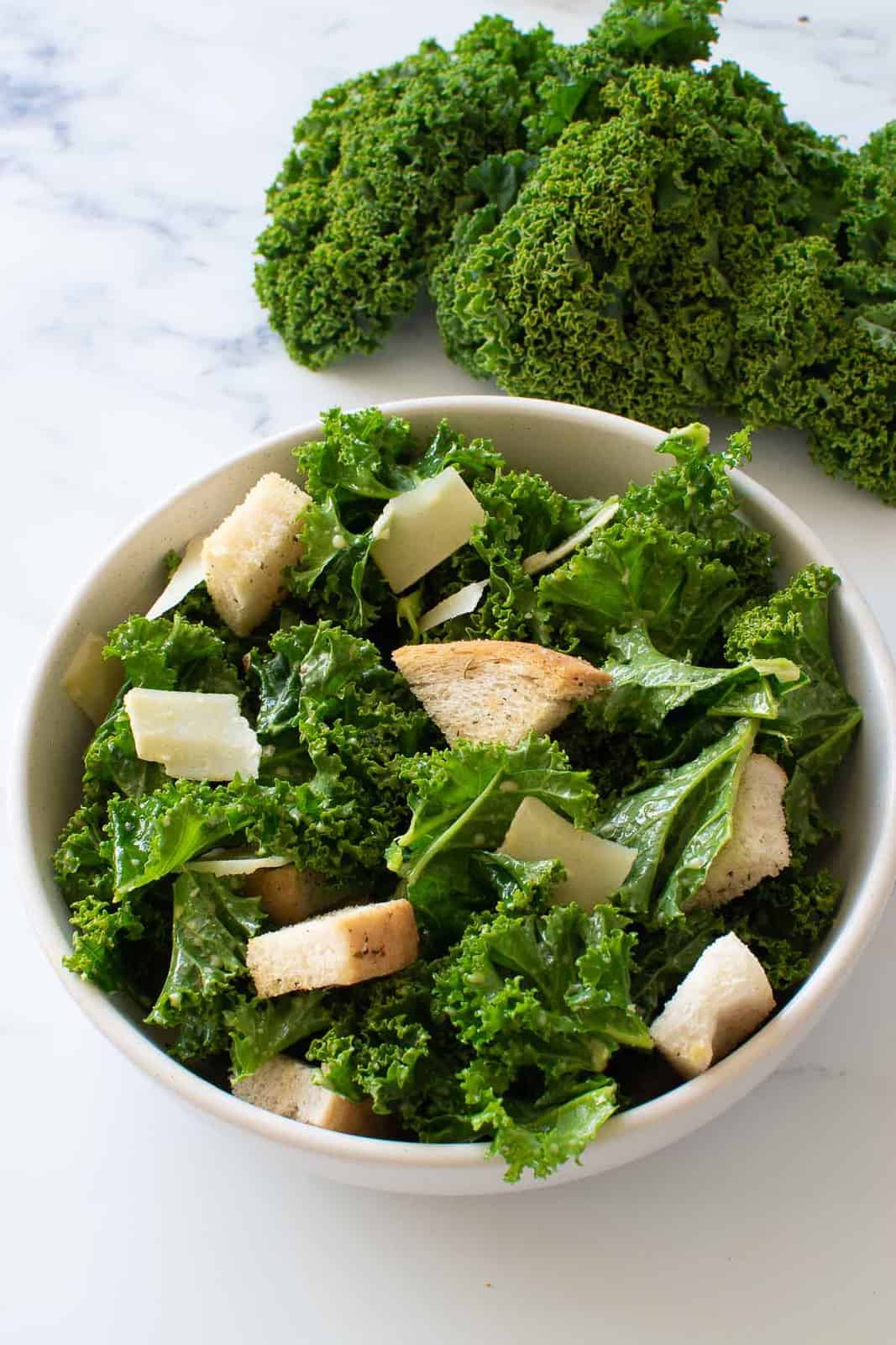 A bowl of kale Caesar salad with Parmesan and croutons.