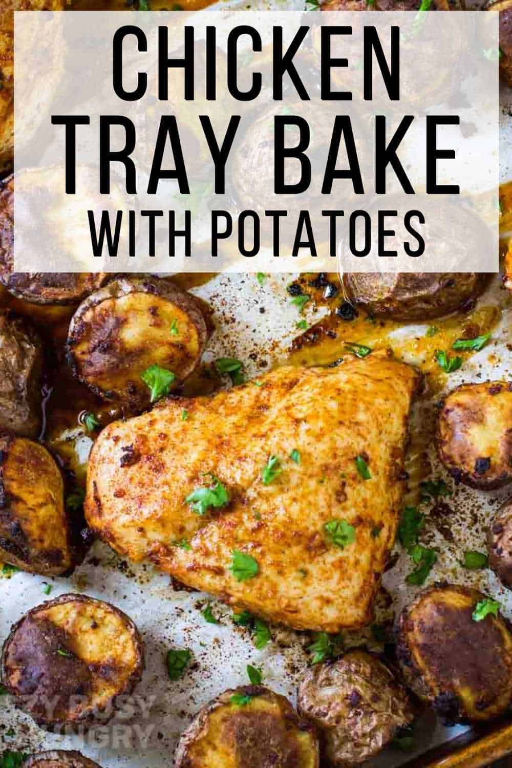 Overhead shot of chicken tray bake on a baking sheet lined with parchment paper garnished with herbs.