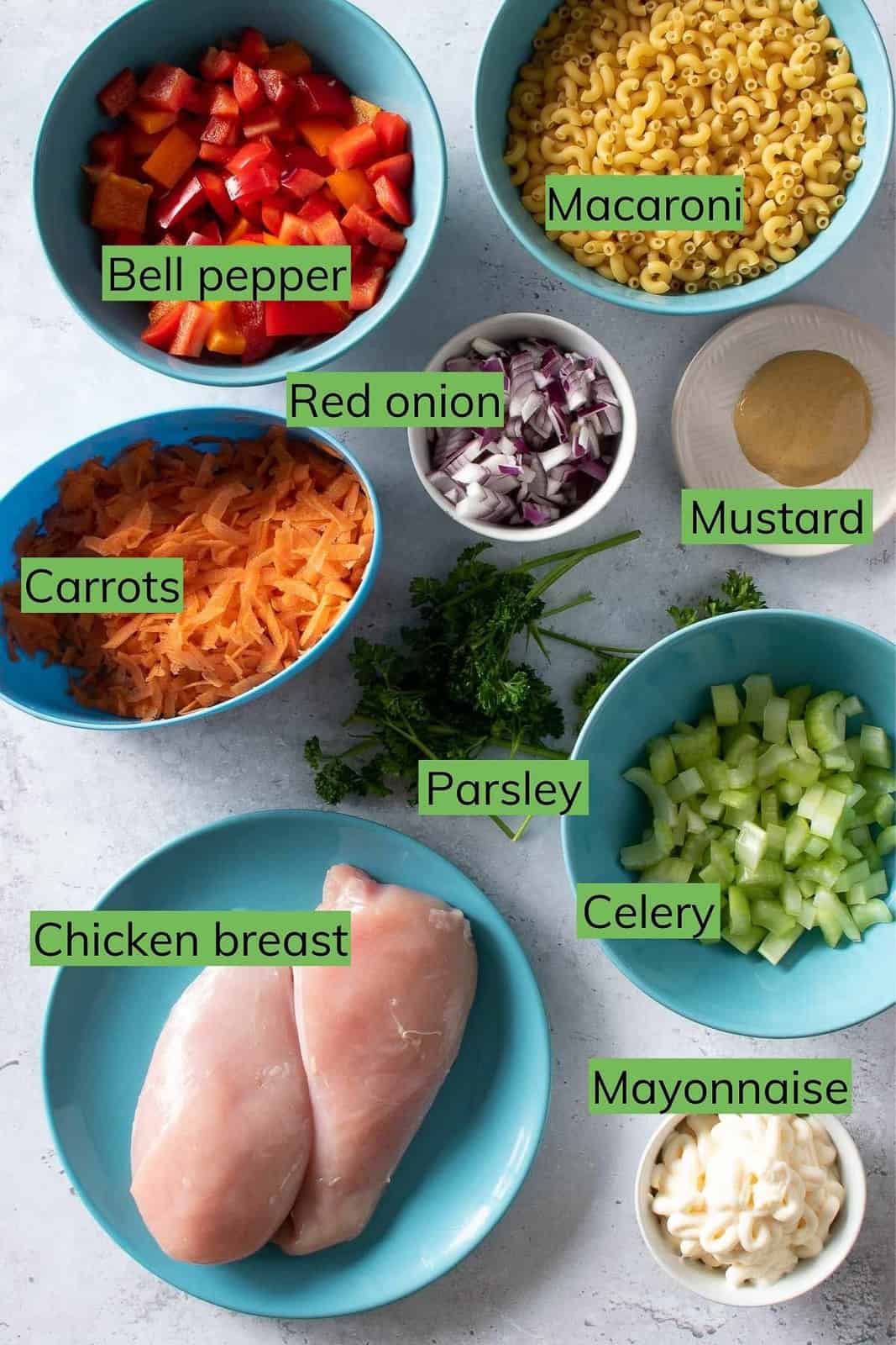 The ingredients needed to make macaroni chicken salad laid out on a table.