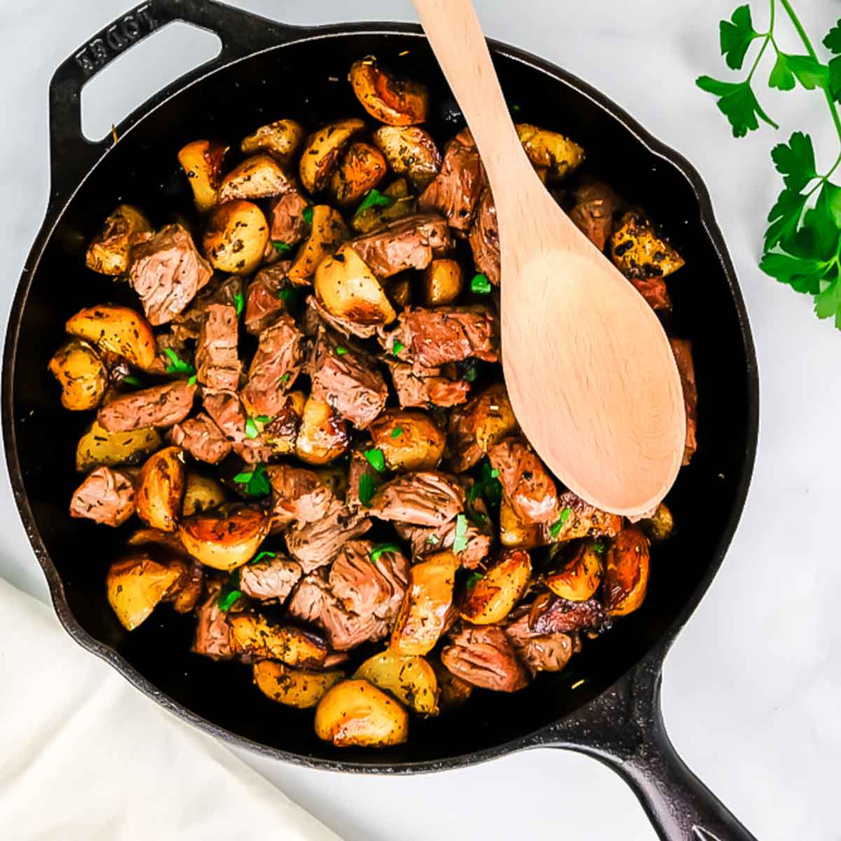 Overhead view of steak bites and potatoes in a black cast iron skillet.