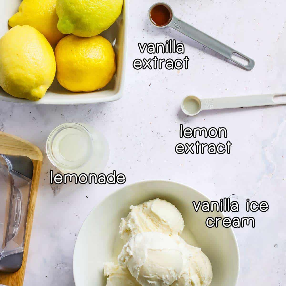 Overhead shot of frosted lemonade ingredients- vanilla extract, lemon extract, lemonade, and vanilla ice cream.