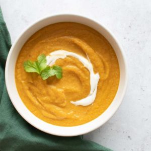 A bowl of carrot and lentil soup, topped with Greek yogurt and cilantro.