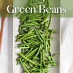 Green beans on a white tray with a wooden spoon.