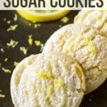 Close up shot of three lemon cookies laying on each other garnished with lemon shavings with a lemon slice in the background.