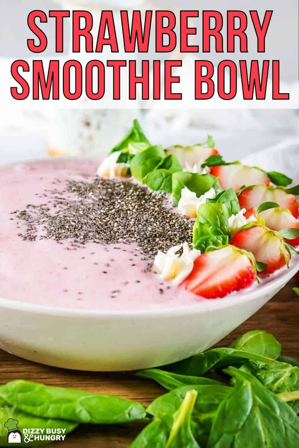 Side view of smoothie bowl garnished with flax seeds, mint, and sliced strawberries on a wooden surface with more mint on the side.