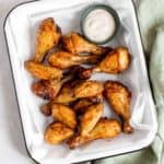 Overhead view of a serving platter of air fryer chicken wings with a ranch dipping sauce.