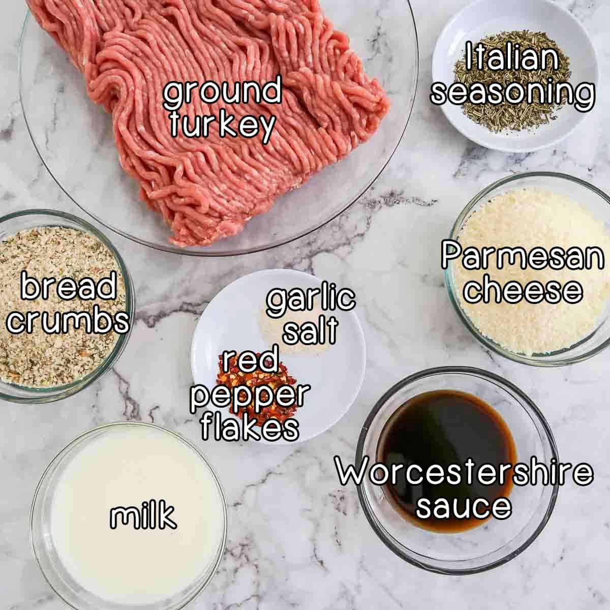 Overhead shot of ingredients- ground turkey, Italian seasoning, bread crumbs, milk, Worcestershire sauce, parmesan cheese, garlic salt, and red pepper flakes.