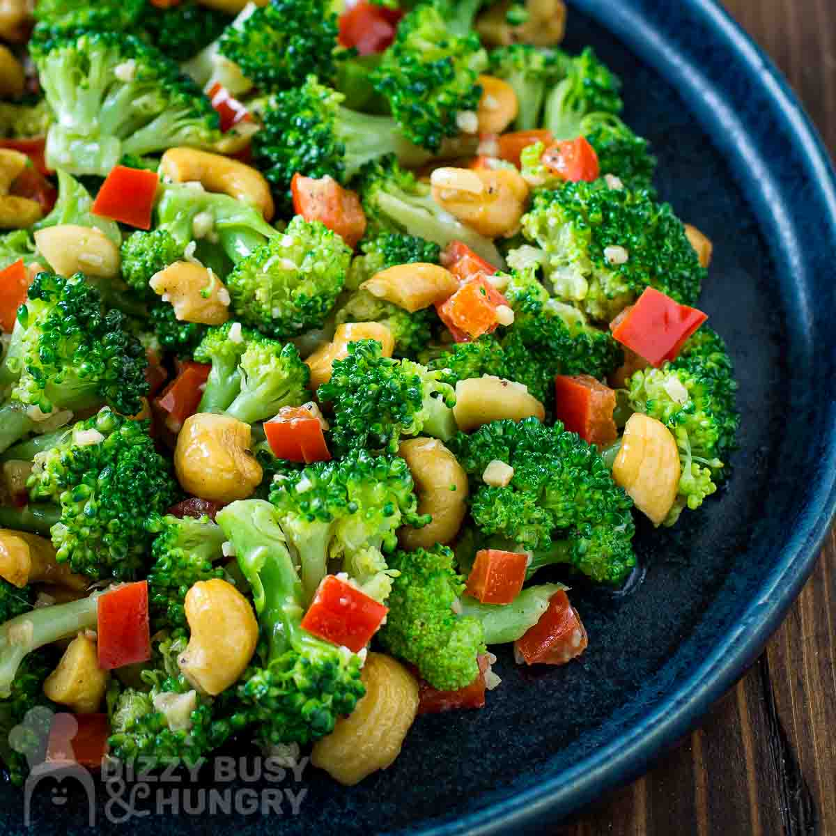 Side view of garlic butter broccoli in a blue bowl on a wooden surface