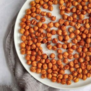 Overhead shot of crispy chickpeas on a white plate on a grey cloth.