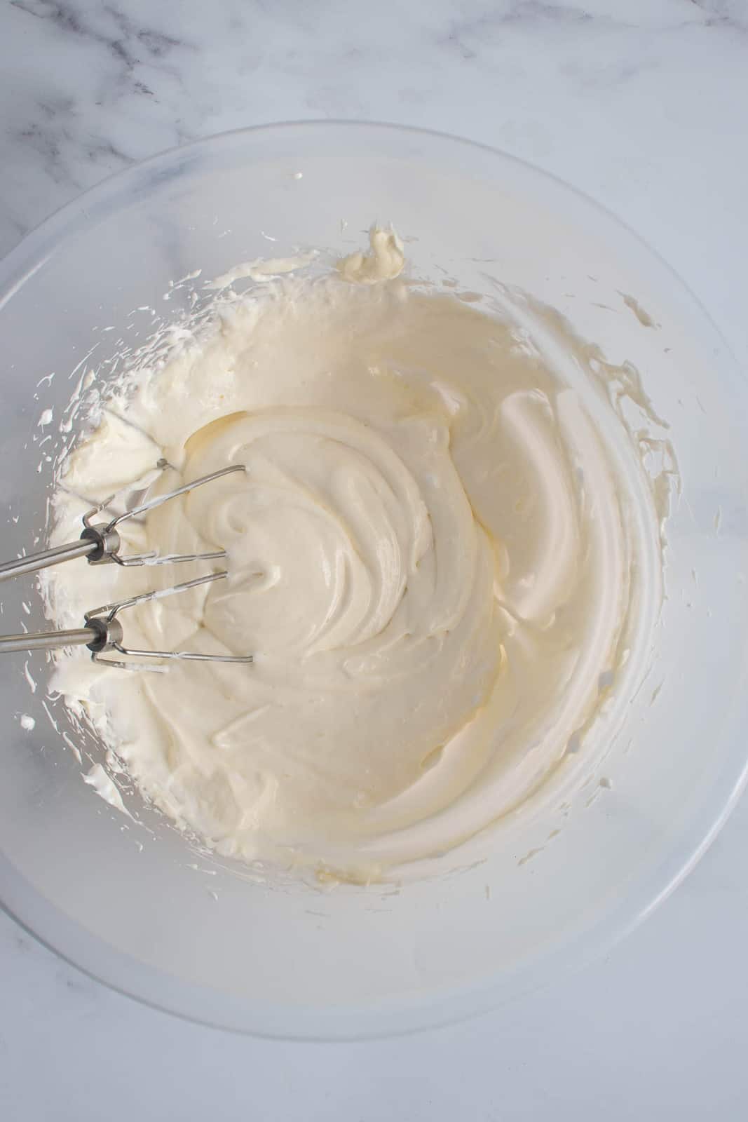 Cream cheese dip in a bowl with an electric mixer.