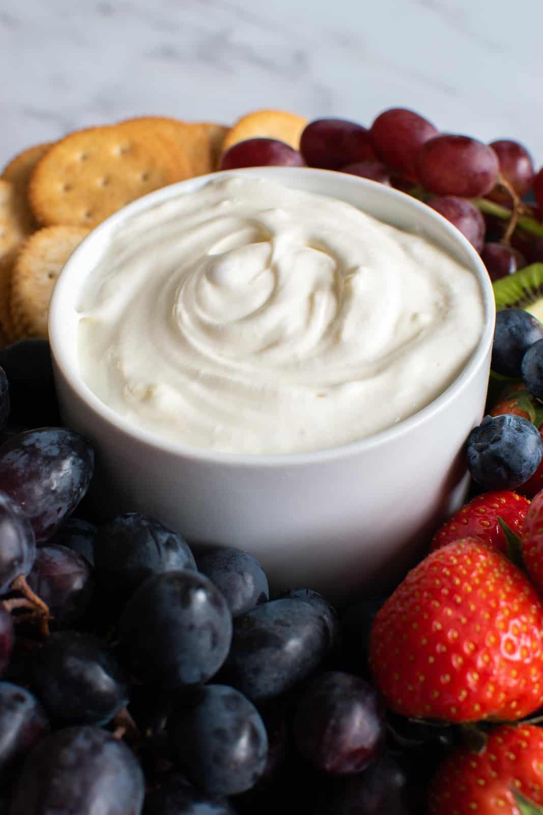 Close up of a dip with marshmallow fluff and cream cheese, surrounded by fruit.