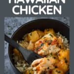 Side shot of Hawaiian chicken in a black bowl with rice and a black fork on the side on a grey marble countertop.