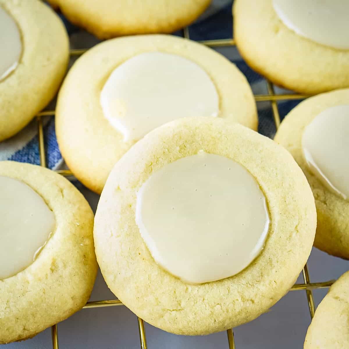 Close up shot of multiple maple thumbprint cookies on a gold drying rack.