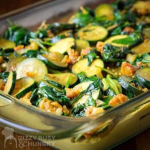 Close up shot of casserole in a clear cooking dish on a wooden surface.