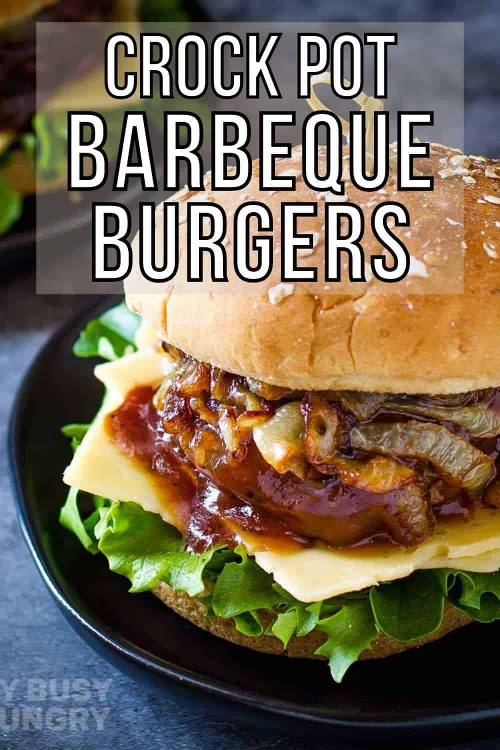 Side shot of barbecue burger with lettuce, cheese, caramelized onions, and a sesame bun on a black plate on a blue surface.