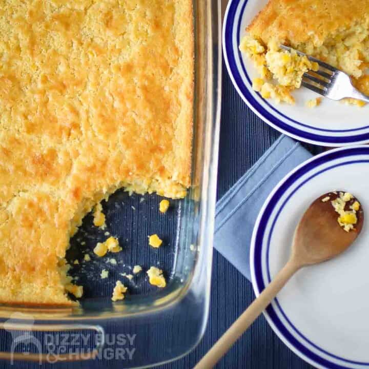 Overhead view of of corn casserole in the casserole dish and on a plate with a wooden spoon on a plate on the side.
