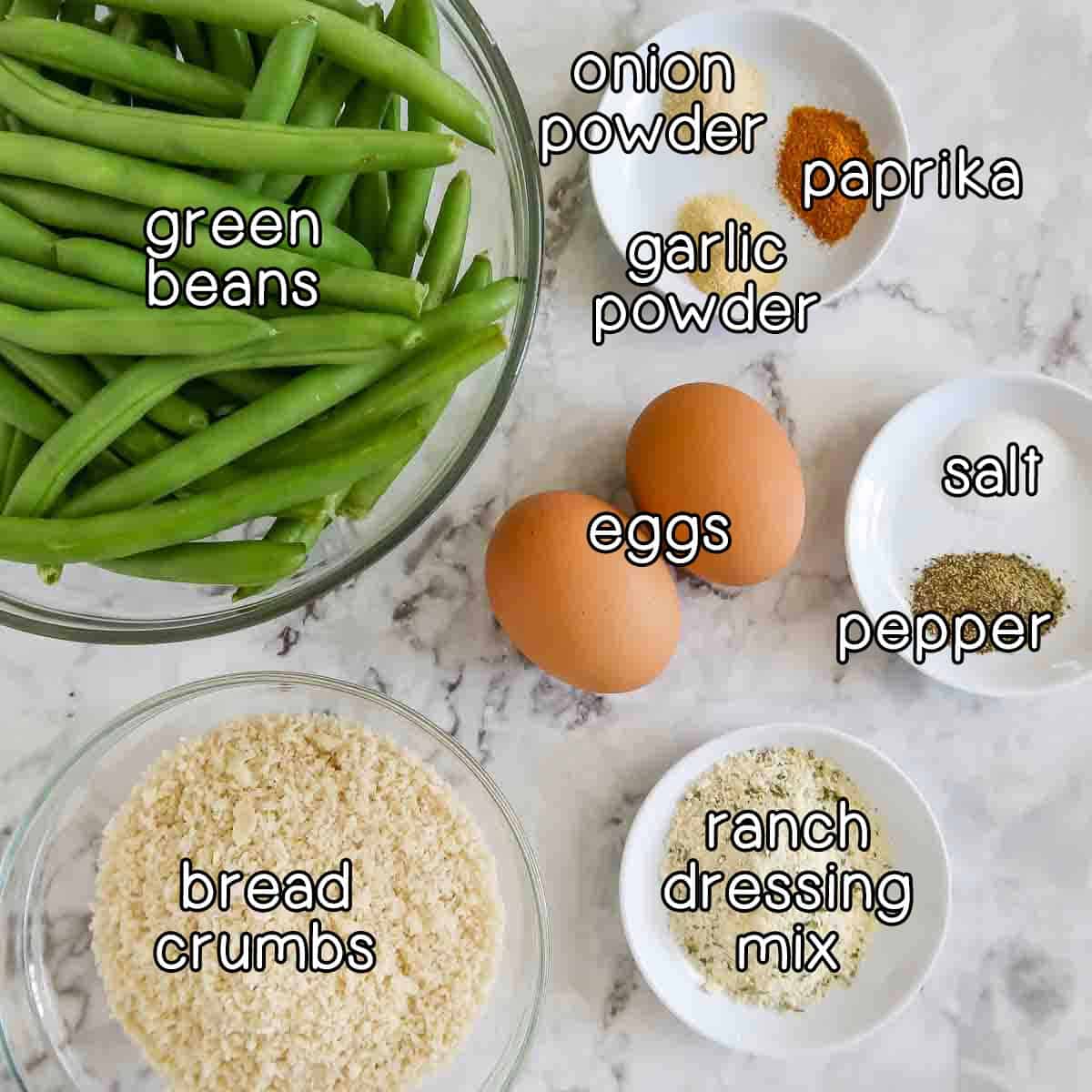 Overhead shot of ingredients- green beans, eggs, bread crumbs, ranch dressing mix, salt and pepper, onion powder, garlic powder, and paprika.