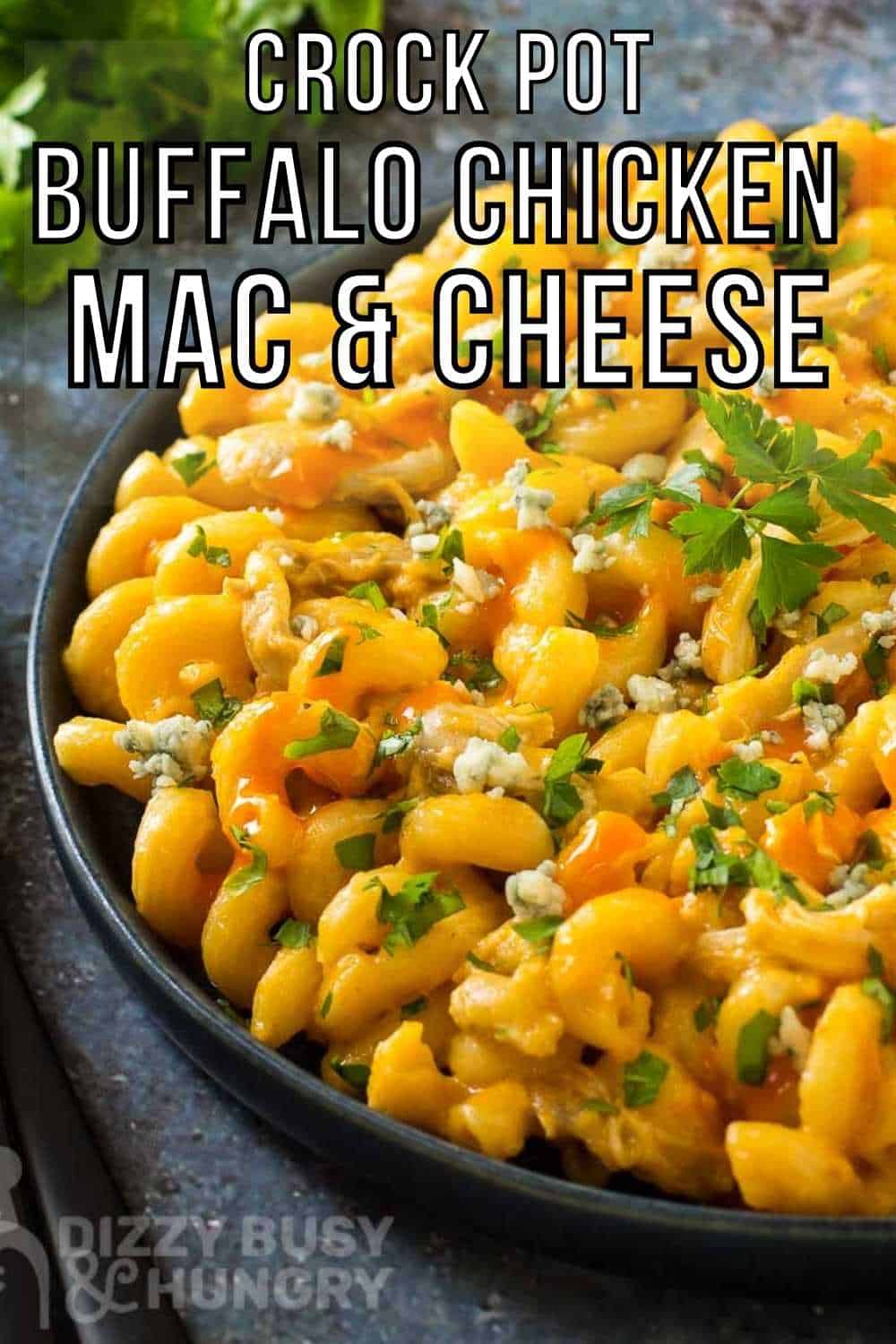 Side close up shot of buffalo Mac and cheese garnished with parsley in a black bowl on a grey and blue marbled surface with a black fork and more parsley in the background.