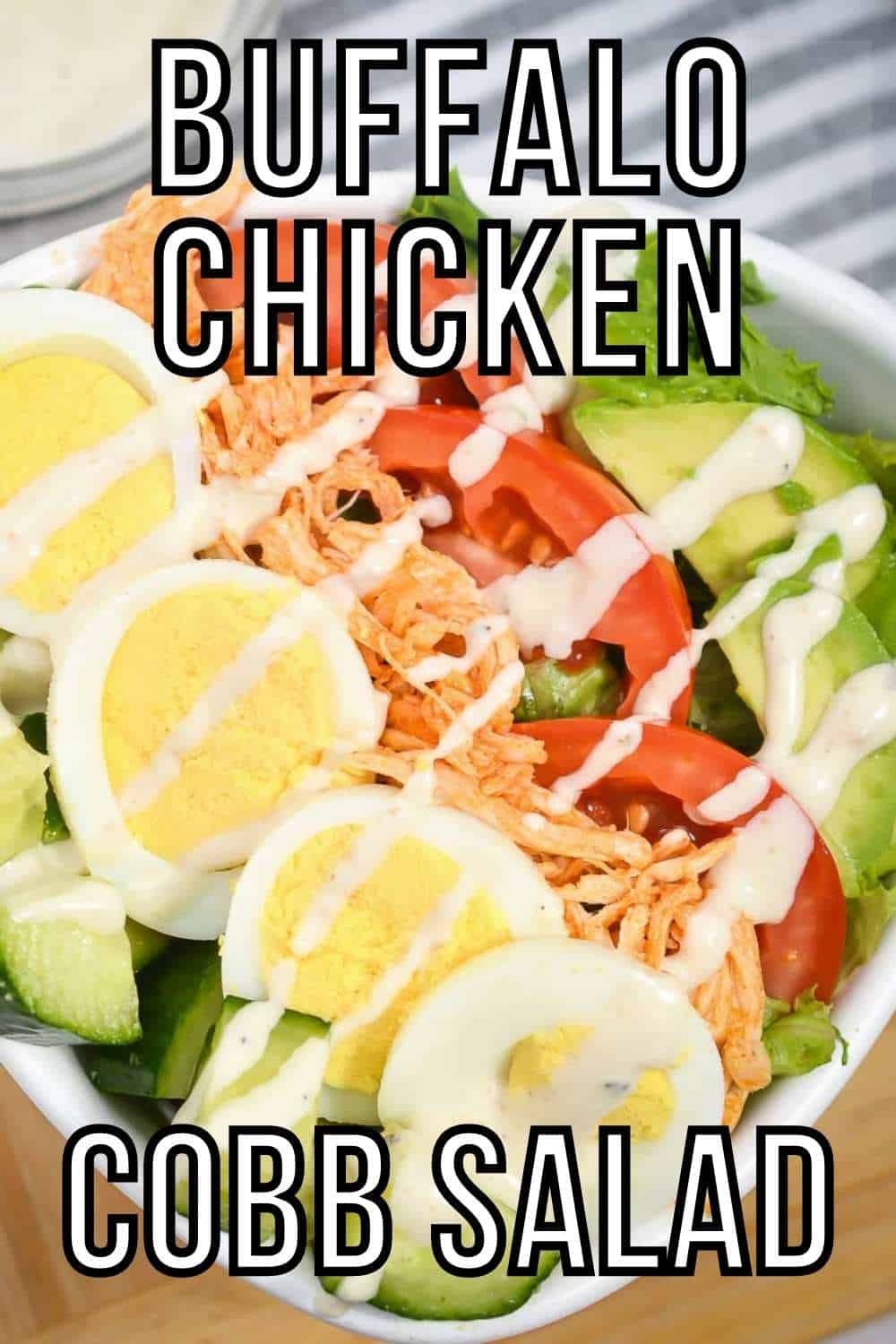 Close up shot of buffalo chicken salad with blue cheese dressing in a white bowl on a grey and white striped cloth with a bowl of blue cheese dressing in the background.
