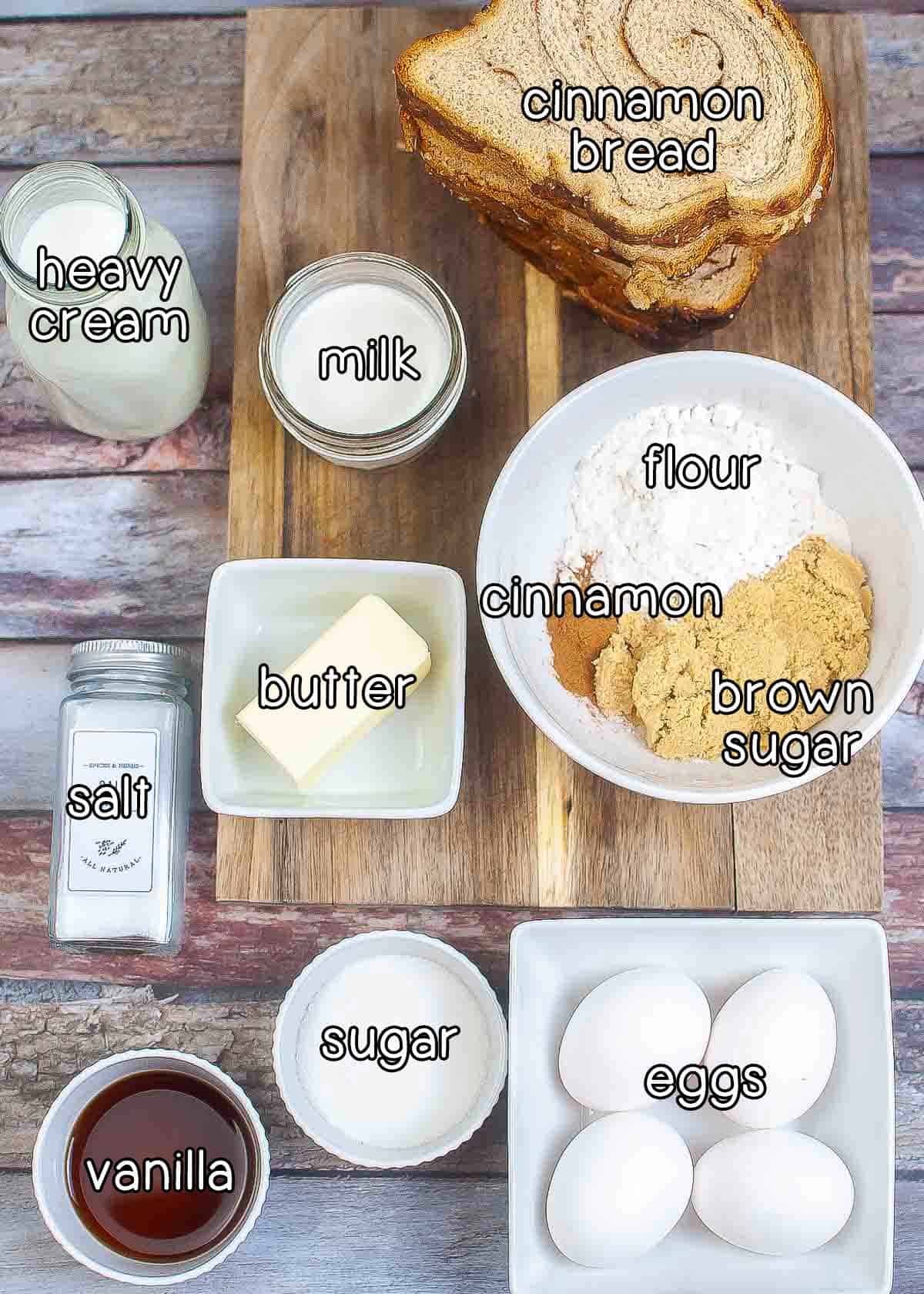 Overhead shot of ingredients - cinnamon bread, milk, heavy cream, salt, butter, flour, cinnamon, brown sugar, vanilla, sugar, and eggs.