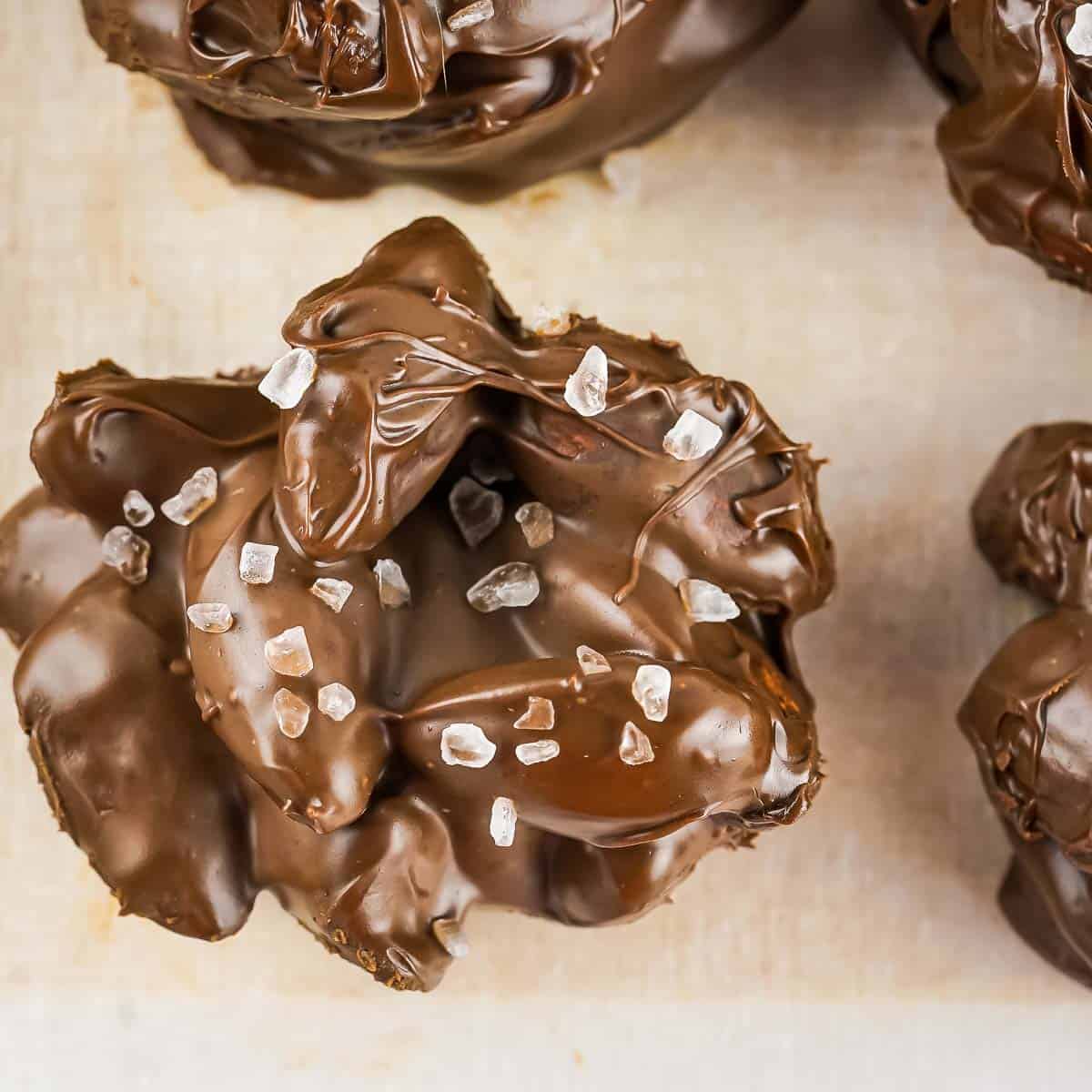 Close up overhead shot of one chocolate nut cluster sprinkled with sea salt on a baking sheet.