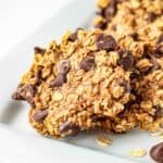 Side close up shot of multiple oatmeal cookies on a white rectangle plate.