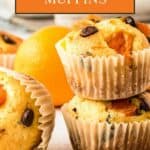 Side view of two stacked muffins and one turned on its side on a white surface with an orange in the background.