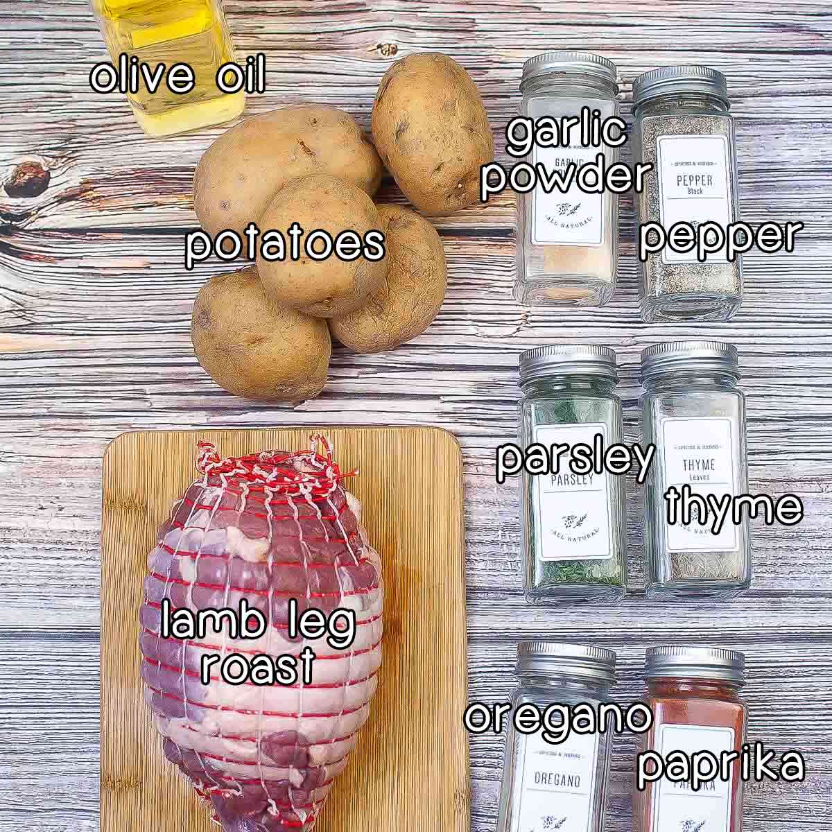 Overhead shot of ingredients - olive oil, potatoes, lamb leg roast, garlic powder, pepper, parsley, thyme, oregano, and paprika.