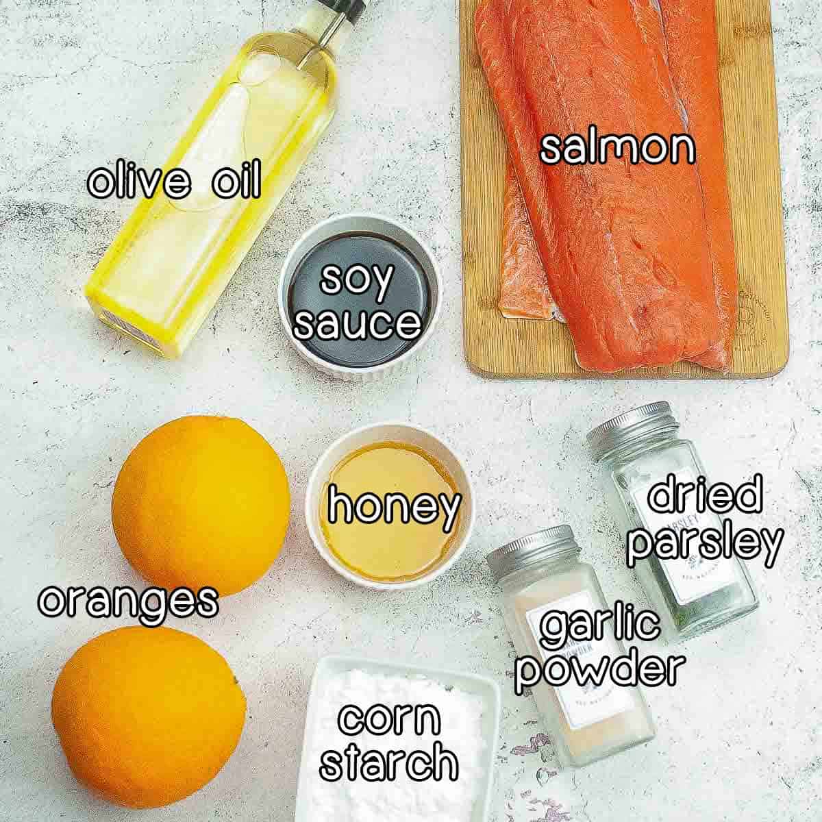 Overhead shot of ingredients - olive oil, salmon, soy sauce, honey, oranges, corn starch, garlic powder, and dried parsley.