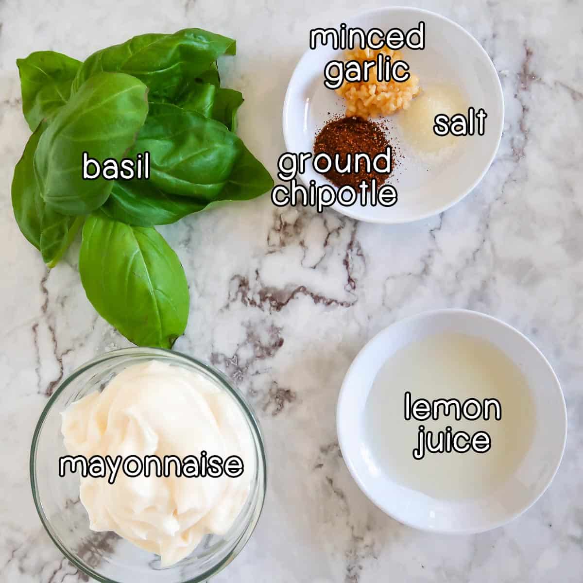 Overhead shot of ingredients - basil, mayonnaise, lemon juice, minced garlic, ground chipotle, and salt.