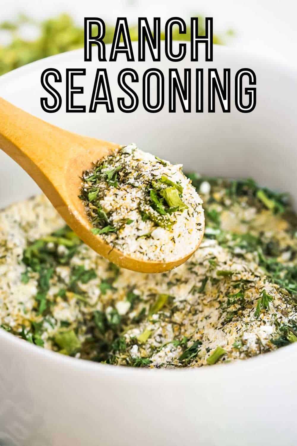 Side close up shot of a wooden spoon scooping some ranch seasoning out of a white bowl.