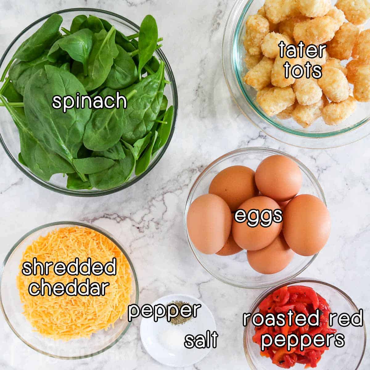 Overhead shot of ingredients - spinach, tater tots, eggs, shredded cheddar, roasted red pepper, pepper, and salt.