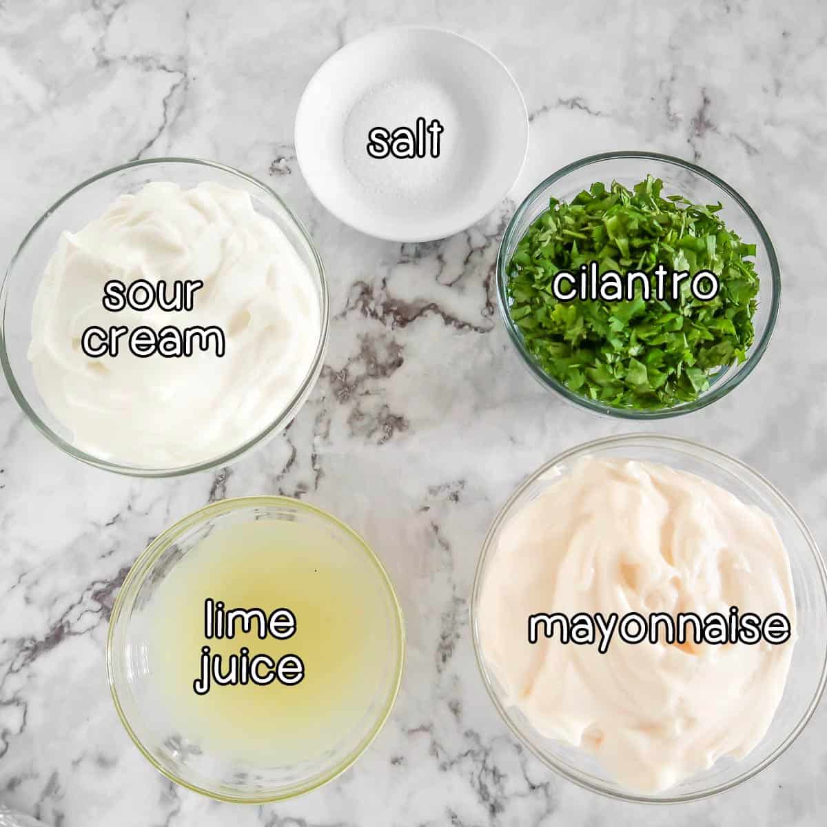 Overhead shot of ingredients - sour cream, salt, cilantro, lime juice, and mayonnaise.