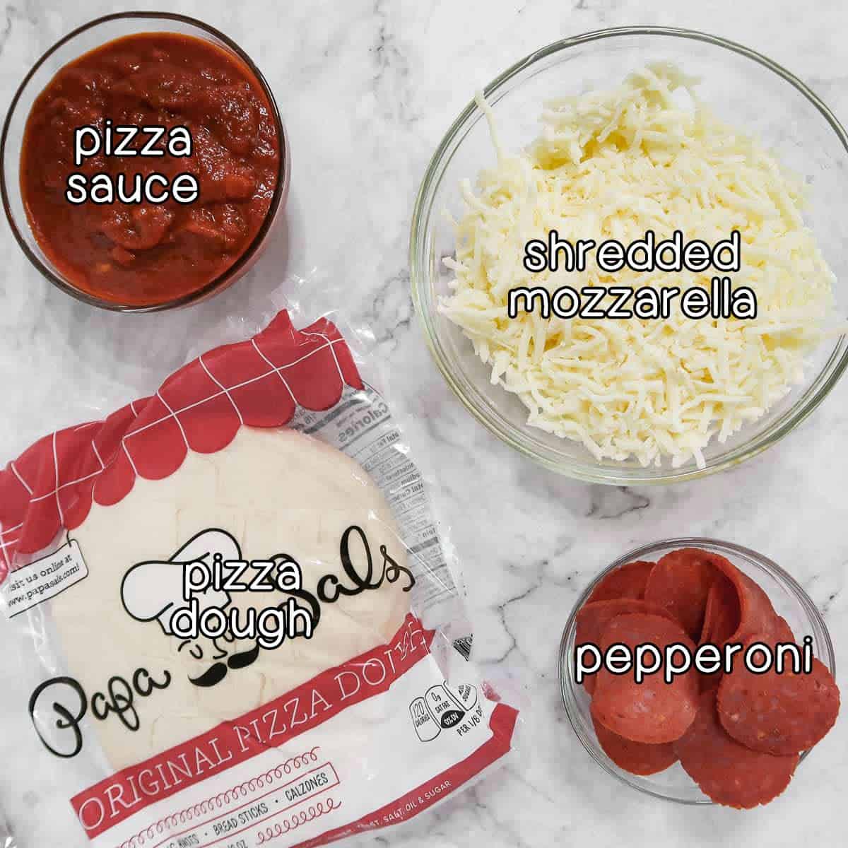 Overhead shot of ingredients - pizza sauce, shredded mozzarella, pepperoni, and pizza dough.