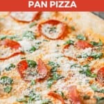 Close up angled shot of full pan pizza garnished with parmesan cheese and basil.