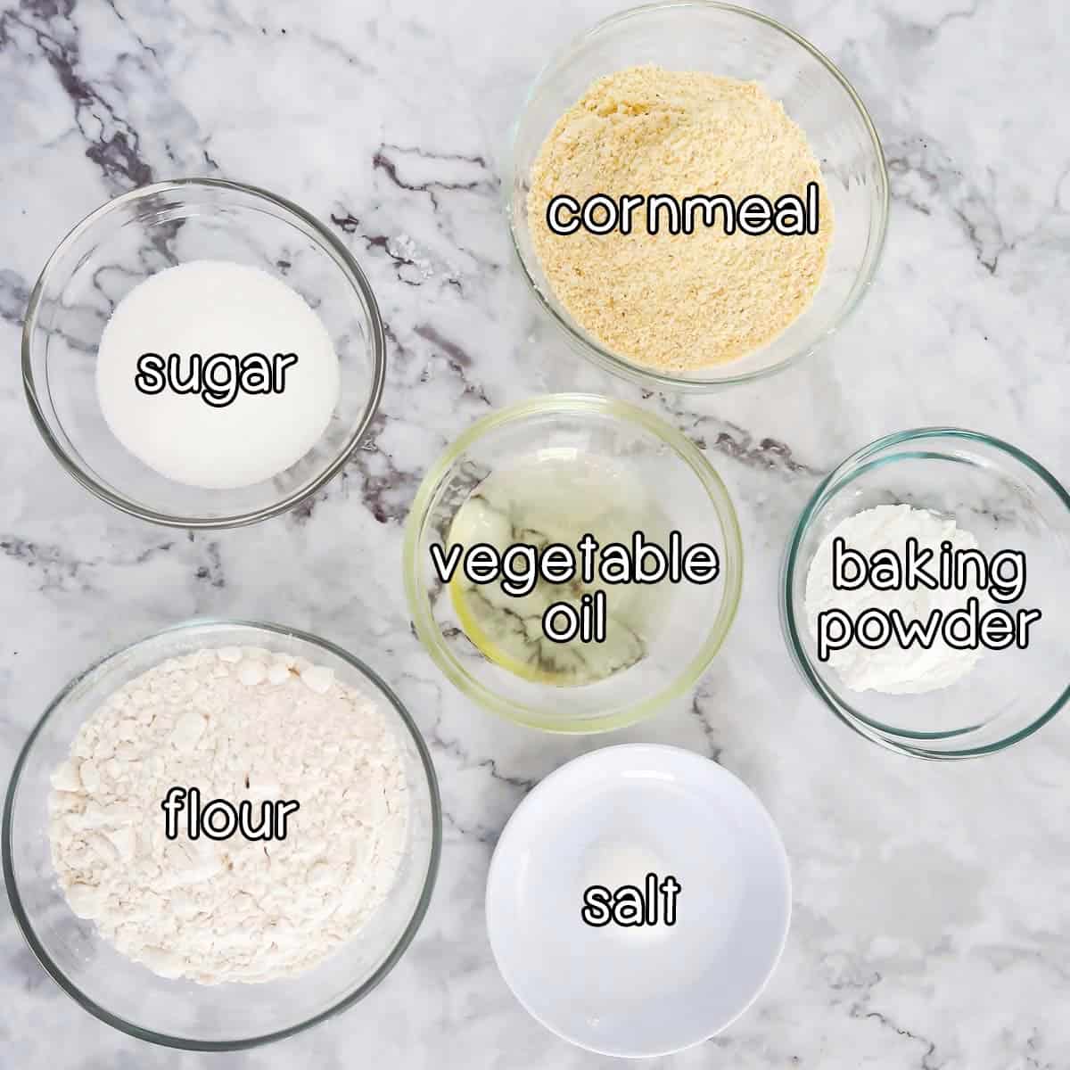 Overhead shot of ingredients - sugar, cornmeal, vegetable oil, baking powder, flour, and salt.